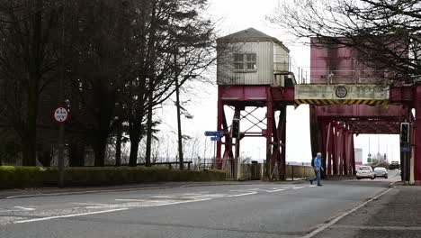 Slow-motion-of-a-man-crossing-the-road-near-the-Bascule-Bridge-in-Renfrew,-Scotland