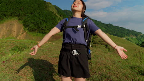 Medium-view-pan-up-along-woman-raising-arms-out-relaxing-and-feeling-the-breeze-on-long-trek-hiking