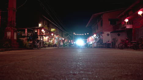 Muslim-woman-in-hijab-driving-scooter-on-lit-street-at-night,-Thailand