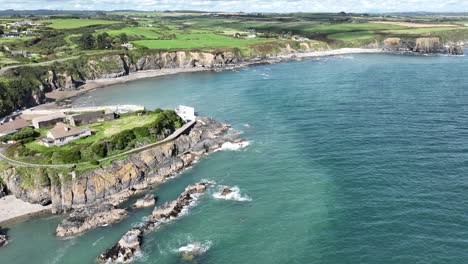 Ireland-Coast-aerial-establishing-shot-of-a-sheltered-fishing-harbour-at-Boatstrand-Copper-Coast-Waterford-on-a-bright-summer-day