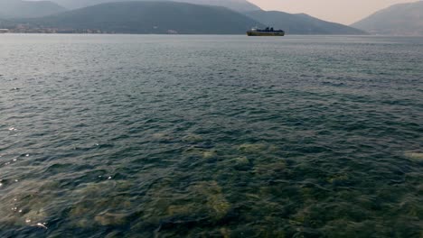 Eine-Filmische-Luftaufnahme-Eines-Strandes-Und-Einer-Fähre,-Die-Auf-Der-Insel-Kefalonia-In-Griechenland-Ankommt