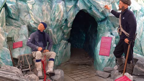 Cueva-Glaciar-Artificial-Con-Dos-Maniquíes-Parados-Afuera,-Acercándose-A-La-Apertura-De-La-Cueva-Oscura-En-El-Museo-Del-Glaciar-Noruego-En-Fjaerland