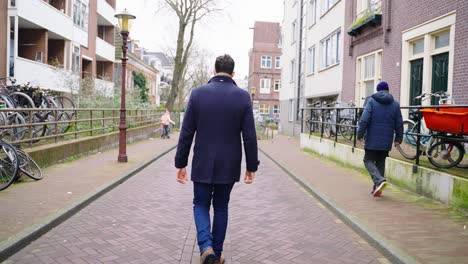 Un-Hombre-Adulto-Con-Su-Chaqueta-Caminando-Por-La-Calle-En-Ámsterdam,-Países-Bajos.