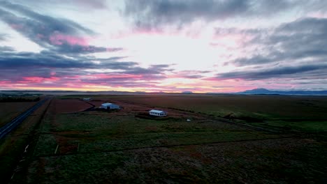 Vista-Aérea-De-La-Granja-En-El-Campo-Con-Cielos-Rosados-Durante-El-Amanecer-En-El-Sur-De-Islandia
