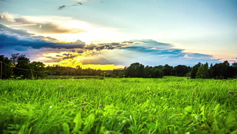 Colorful-low-angle-sunset-time-lapse-over-a-grassy-countryside-meadow