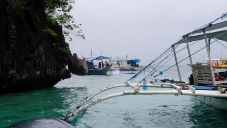 Outrigger-tour-boat-with-tourist-arriving-at-popular-tourism-destination-on-island-hopping-tour-in-Palawan,-Philippines