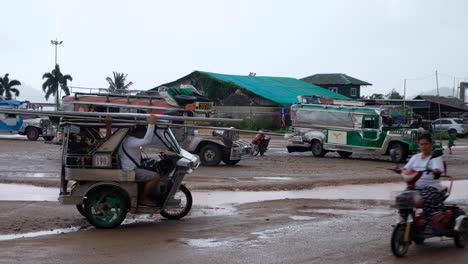 Filipino-tricycle-taxis-and-bus-transport-during-wet-season-on-a-wet-and-rainy-day-in-Coron,-Palawan,-Philippines