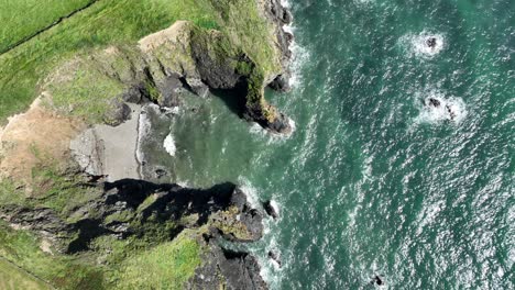 Coast-Ireland-aerial-looking-down-on-a-sheltered-cove-with-sea-arch-Copper-Coast-Waterford-Ireland