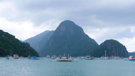 Scenic-landscape-view-of-island-hopping-tour-boats-against-tropical-island-backdrop-in-popular-tourism-destination-of-El-Nido-in-Palawan,-Philippines