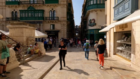 Schöne-Straßenansichten-Der-Valletta-Architektur-Mit-Schaufenstern-Mit-Menschen,-Die-In-Malta-Einkaufen-Und-Herumlaufen