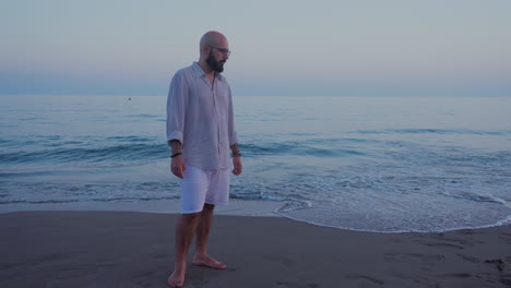 Man-standing-at-the-sandy-beach-after-sundown