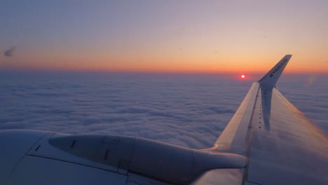 Flugzeugflügel-Fliegt-über-Einem-Wolkenbett-Mit-Einem-Sonnenuntergang-Am-Horizont