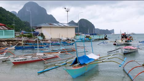 Traditionelle-Bunte-Auslegerfischerboote-Vertäut-Im-Meer-Mit-Tropischen-Inseln-In-Der-Ferne-In-El-Nido,-Palawan,-Philippinen
