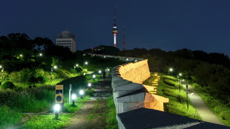 Timelapse-Nocturno-De-Personas-Caminando-Por-Hanyangdoseong,-Muralla-De-La-Ciudad-De-Seúl-En-El-Parque-Namsan-Con-Vista-Icónica-De-La-Torre-N-De-Seúl---Alejamiento-Dinámico