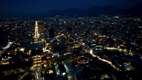 Tirana-by-night,-aerial-view-of-panoramic-capital-city-with-high-buildings,-museum,-stadium,-pyramid-and-boulevard-lights