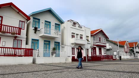 Woman-walking-alone-in-Costa-Nova-with-small-colorful-houses-in-background