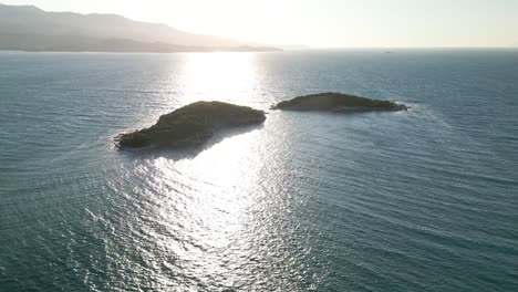 La-Luz-Del-Sol-Se-Refleja-Sobre-Pequeñas-Olas-En-El-Mar-Azul-Con-Las-Montañas-De-Albania-Al-Fondo.