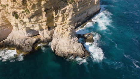 Aerial-view-around-steep-seaside-cliffs-on-the-shore-of-Malta,-on-a-sunny-day