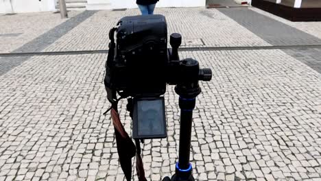 Tripod-with-a-camera-in-vertical-mode-ready-to-take-a-picture-of-a-woman-in-Aveiro