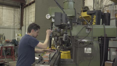 Hombre-Trabajando-Con-Una-Máquina-Industrial-Agarrando-Baldosas-Metálicas-Y-Engrasándolas.