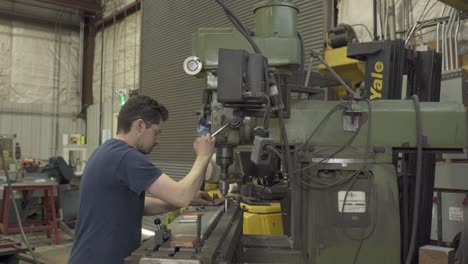 man-turning-handle-down-on-industrial-machine-to-drill
