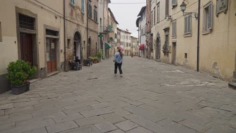 Mujer-Caminando-Por-Una-Calle-Típica-De-La-Ciudad-De-Lucignano-En-Arezzo,-Italia