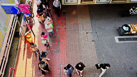 Zeitlupenaufnahme-Einer-Warteschlange-Am-Tag-Und-Vorbeifahrender-Fußgänger-Auf-Einer-Straße-In-Hongkong