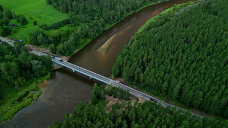 Bridge-crossing-a-river-in-the-forest-countryside---tilt-down-aerial
