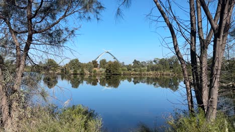 View-through-the-bordering-trees-of-Australian-bush-to-Matagarup-Bridge-in-Perth,-Western-Australia