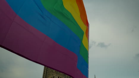 Un-Primer-Plano-De-Una-Colorida-Bandera-Lgbt-Ondeando-Con-El-Telón-De-Fondo-Del-Palacio-De-La-Cultura-Y-La-Ciencia-En-Varsovia,-Situado-En-La-Plaza-Principal-En-El-Corazón-De-La-Capital