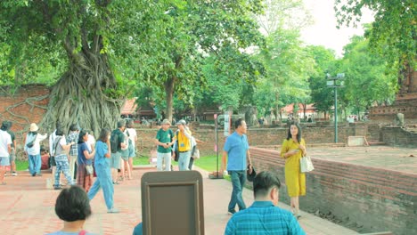 Touristen-Versammeln-Sich-Um-Den-Buddhistischen-Kopf,-Der-In-Baumwurzeln-An-Der-Historischen-Stätte-Von-Ayutthaya-In-Thailand-Verschlungen-Ist