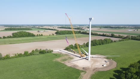 USA-flag-wave-in-construction-site-of-wind-turbine,-aerial-view
