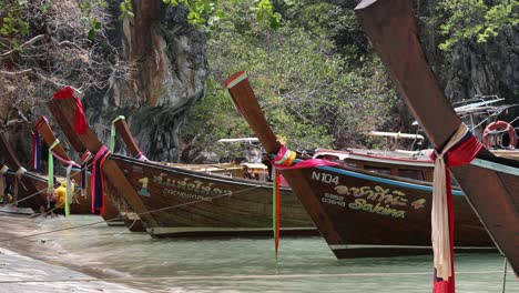 Traditional-long-tail,-wooden-boats-with-colorful-and-decorative-ribbons-bring-tourists-to-Koh-Lao-La-Ding-island,-near-Krabi,-Thailand