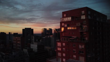 The-city-of-Buenos-Aires-at-sunset,-shot-from-the-sky,-the-drone-flies-at-the-level-of-a-brick-building