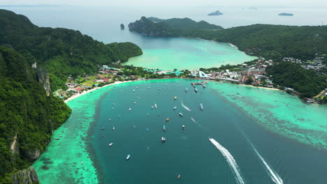 Scenic-turquoise-water-landscape-of-Kho-Phi-Phi-Island,-Boats-sailing-across-the-beach-water,-Aerial-Shot