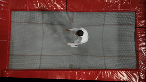 A-man-in-white-clothes-jumping-on-a-trampoline-top-view