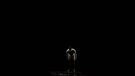 A-man-in-white-doing-acrobatics-on-a-black-background-in-slow-motion
