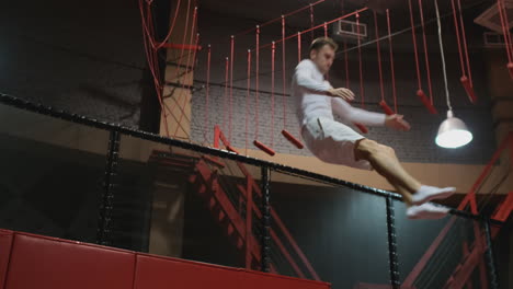 Acrobat-gymnast-jumping-on-a-trampoline-in-the-trampoline-center-in-white-clothes