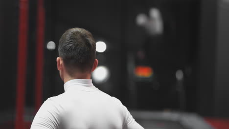 Man-in-trampoline-center-back-view-watching-other-people-jumping-in-the-background