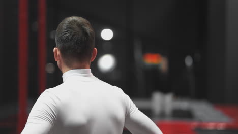 Gimnasta-Masculino-En-El-Centro-Del-Trampolín-Observando-La-Realización-De-Trucos-Rivales.