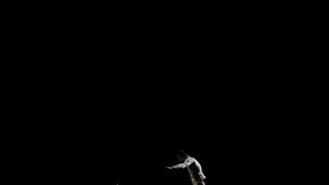 A-handsome-Male-gymnast-in-white-does-acrobatic-stunts-on-a-black-background-in-slow-motion,-rotation-and-flips.-Feeling-of-flight-and-freedom.