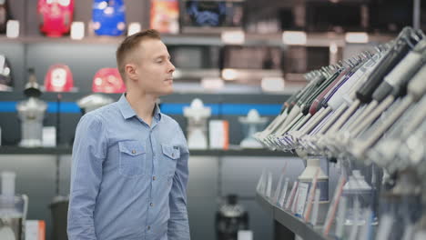 A-young-man-in-a-shirt-chooses-a-blender-for-his-kitchen-in-a-consumer-electronics-store