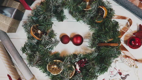 top-view-Christmas-wreath-on-craft-background,-pretty-famale-hand-decorate-christmas-wreath,-motion-shot