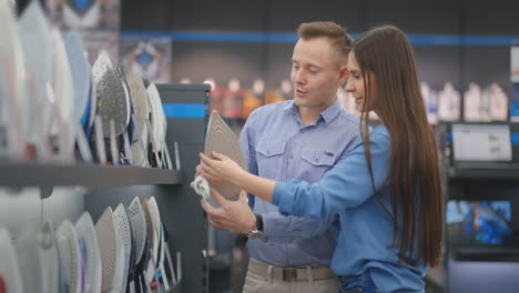 Young-married-couple-chooses-an-iron-to-buy-in-a-new-home-in-an-appliance-store