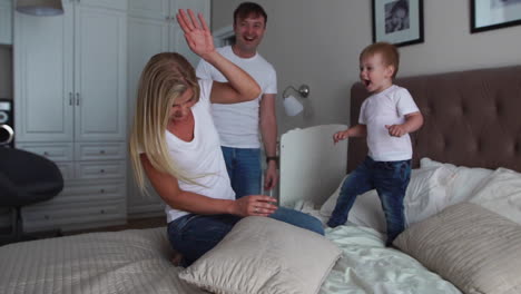 Parents-having-fun-with-their-little-daughter-on-bed.-Family-spending-time-at-the-morning