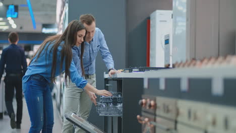 Couple-man-and-woman-to-open-the-door-of-dishwasher-appliances-in-the-store-and-compare-with-other-models-to-buy-the-new-house