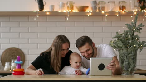 Familien-,-Elternschafts--Und-Menschenkonzept---Glückliche-Mutter-Und-Vater-Zeigen-Dem-Baby-Zu-Hause-Einen-Tablet-PC