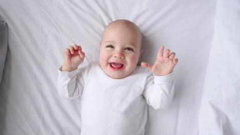 Porträt-Eines-Niedlichen-Lächelnden-Babys,-Das-Zu-Hause-Auf-Dem-Bett-Liegt,-Draufsicht