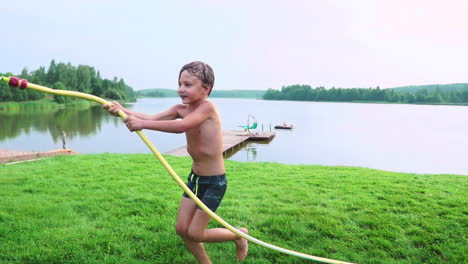 Boy-in-summer-swimming-trunks-pours-water-on-his-younger-brother-having-fun-in-the-Park-on-the-grass-near-the-lake