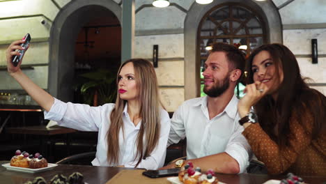 Young-woman-taking-selfie-with-friends-in-restaurant